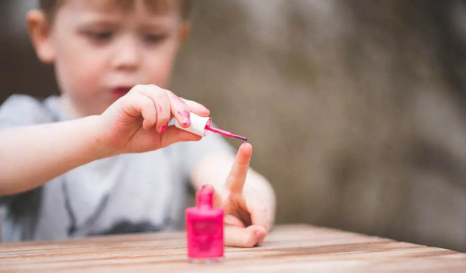 närbild pojke målar naglarna med rosa nagellack